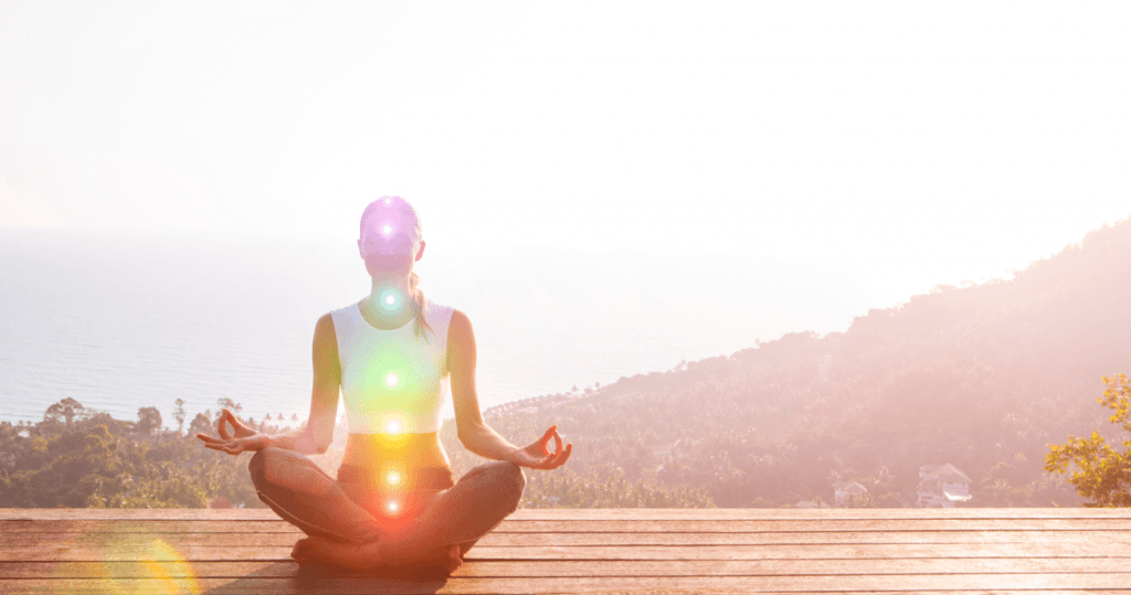 Woman sitting in meditation with lit up chakras